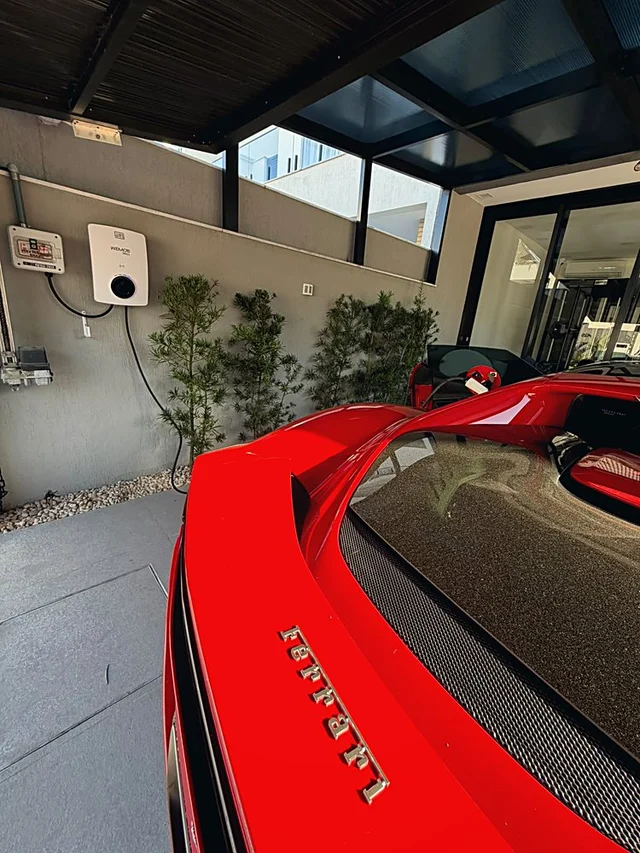 Detalhe da recarga conectada à Ferrari na garagem